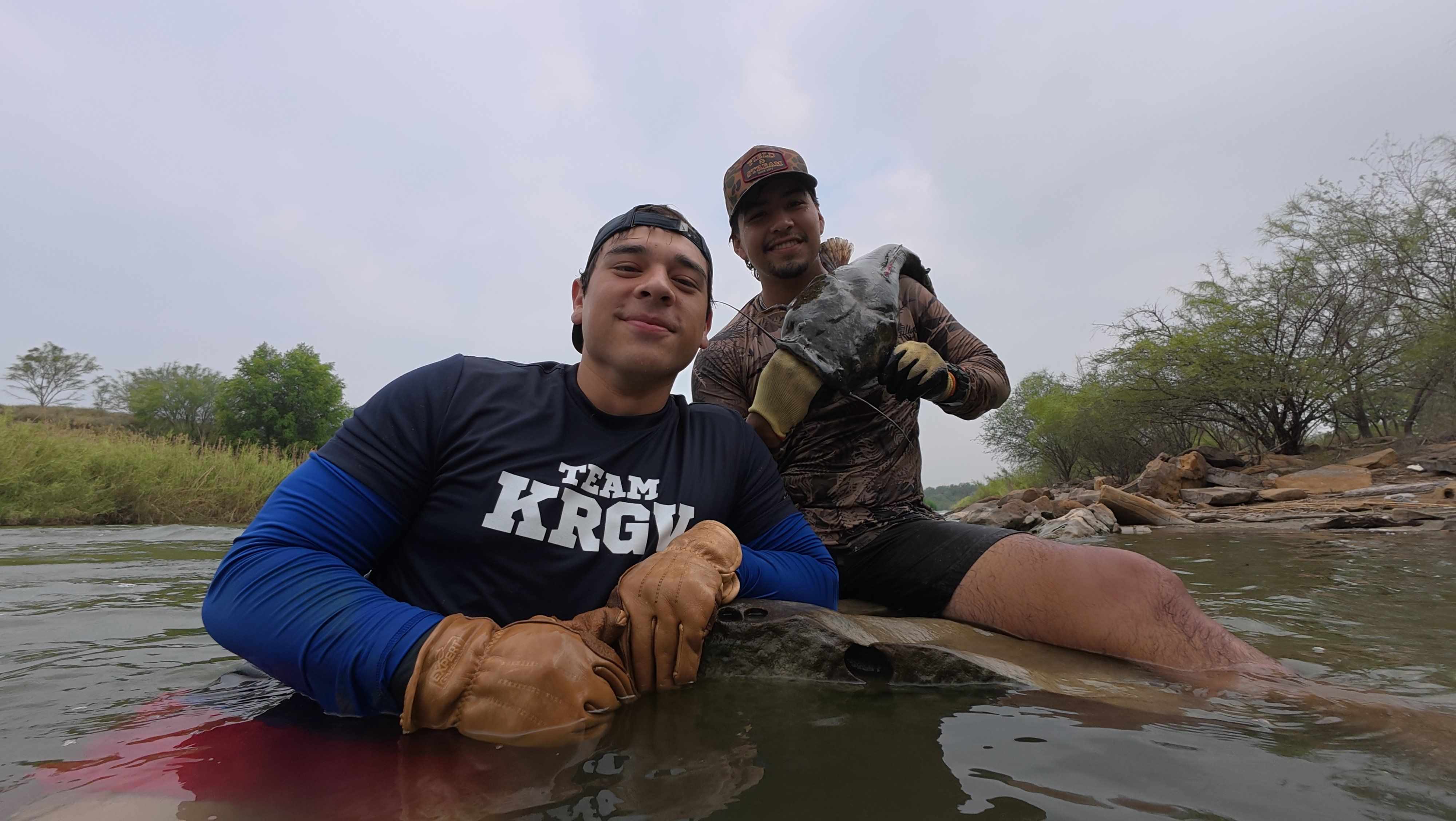 Noodlers wading the river with a hand-grabbed catfish